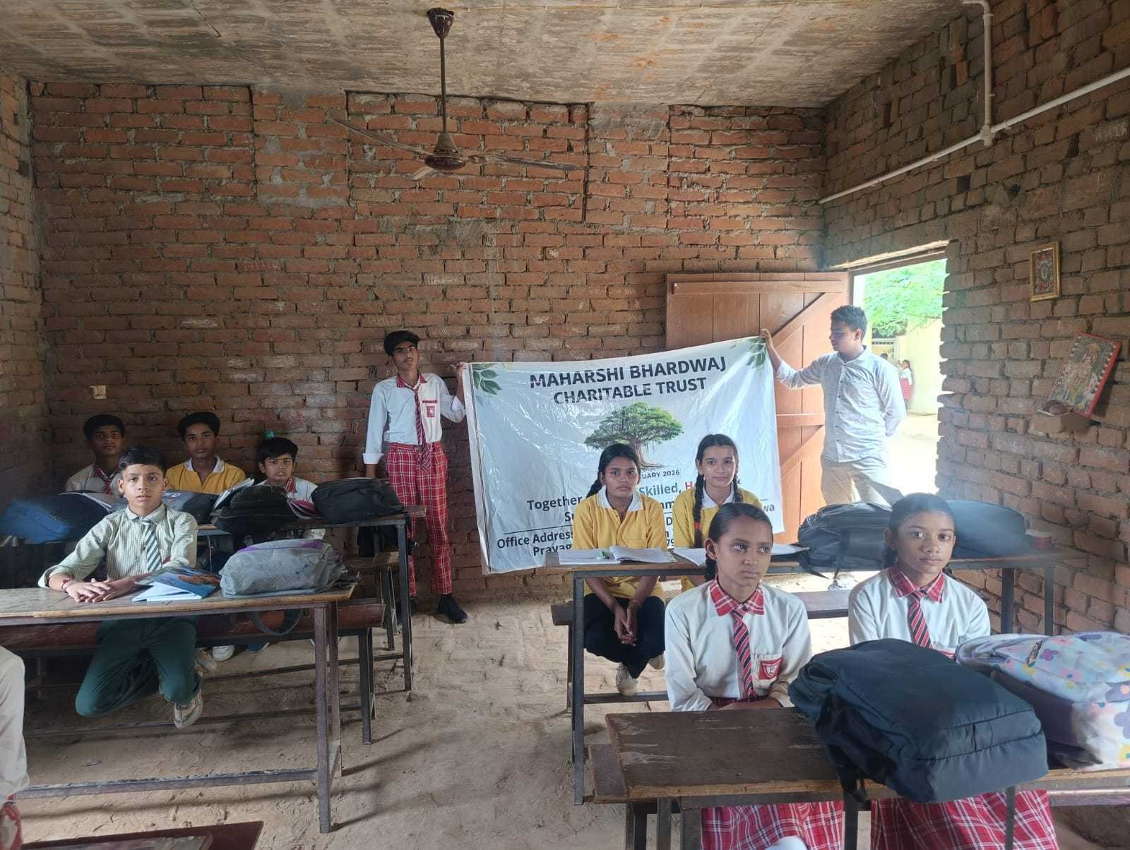 Students holding the Maharshi Bhardwaj Charitable Trust banner in a classroom